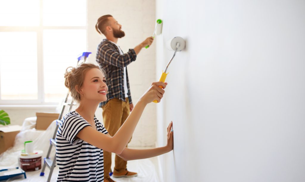 para młodych ludzi maluje ścianę w mieszkaniu.