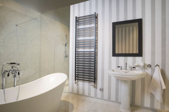 bathroom with wallpaper on the wall, black radiator, mirror in a black frame